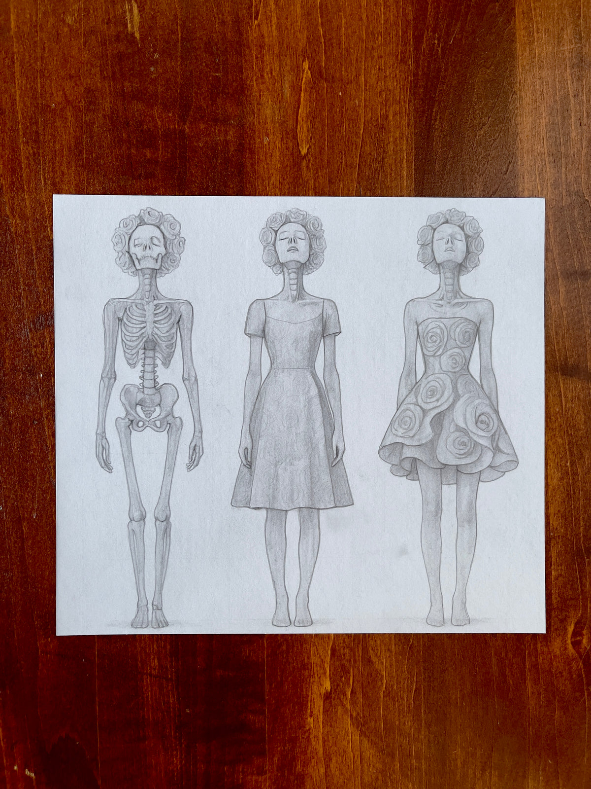 Seth Jennemann MEFREEK – “All That’s Left Is To Let Go” – pencil croquis drawing in contemporary surreal fashion illustration style. Three faceless figures evolve from skeleton to clothed form to floral embodiment, each crowned with roses and depicted in detailed anatomical precision.
