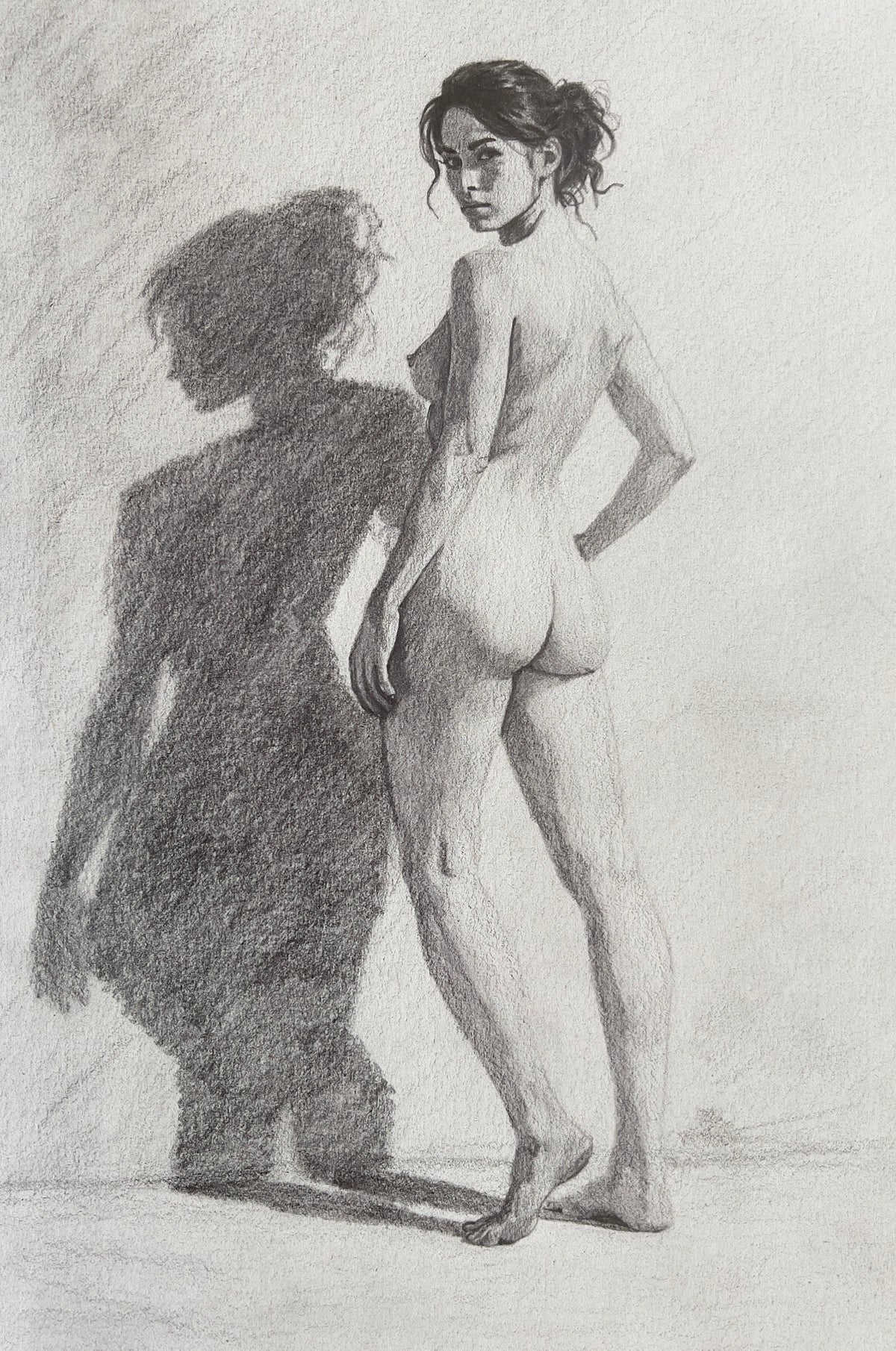 MEFREEK Seth Jennemann Graphite Drawing of a nude female figure standing with strong backlighting casting a bold shadow silhouette beside her emphasizing contrast form and dramatic lighting on textured paper