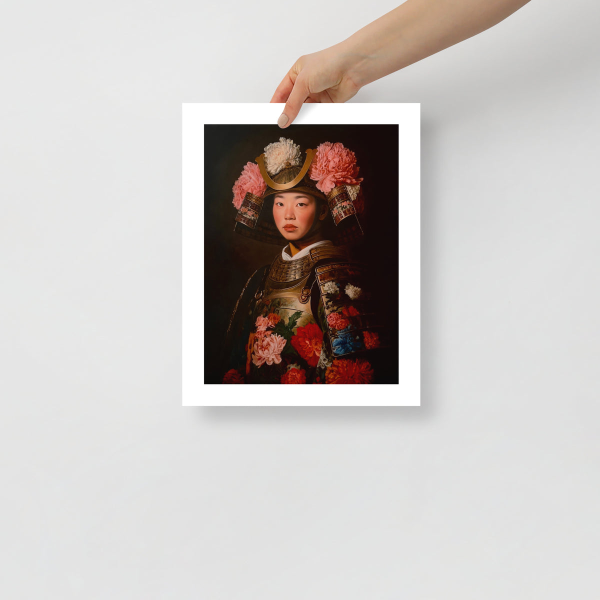 MEFREEK Seth Jennemann Open Edition Art Prints Best Wishes From A Safe Distance – Unframed fine art print held by hand against a light gray background, showing a Japanese woman in traditional samurai armor embellished with vibrant red, pink, orange, blue and white flowers. Her ornate helmet features a golden crescent crest and large chrysanthemum blossoms against a dark, dramatic backdrop.
