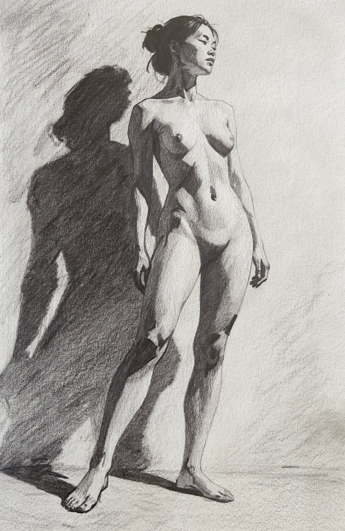MEFREEK Seth Jennemann Graphite Pencil Drawing dramatic nude female figure with strong directional lighting casting a bold shadow high contrast form and anatomical structure on textured paper