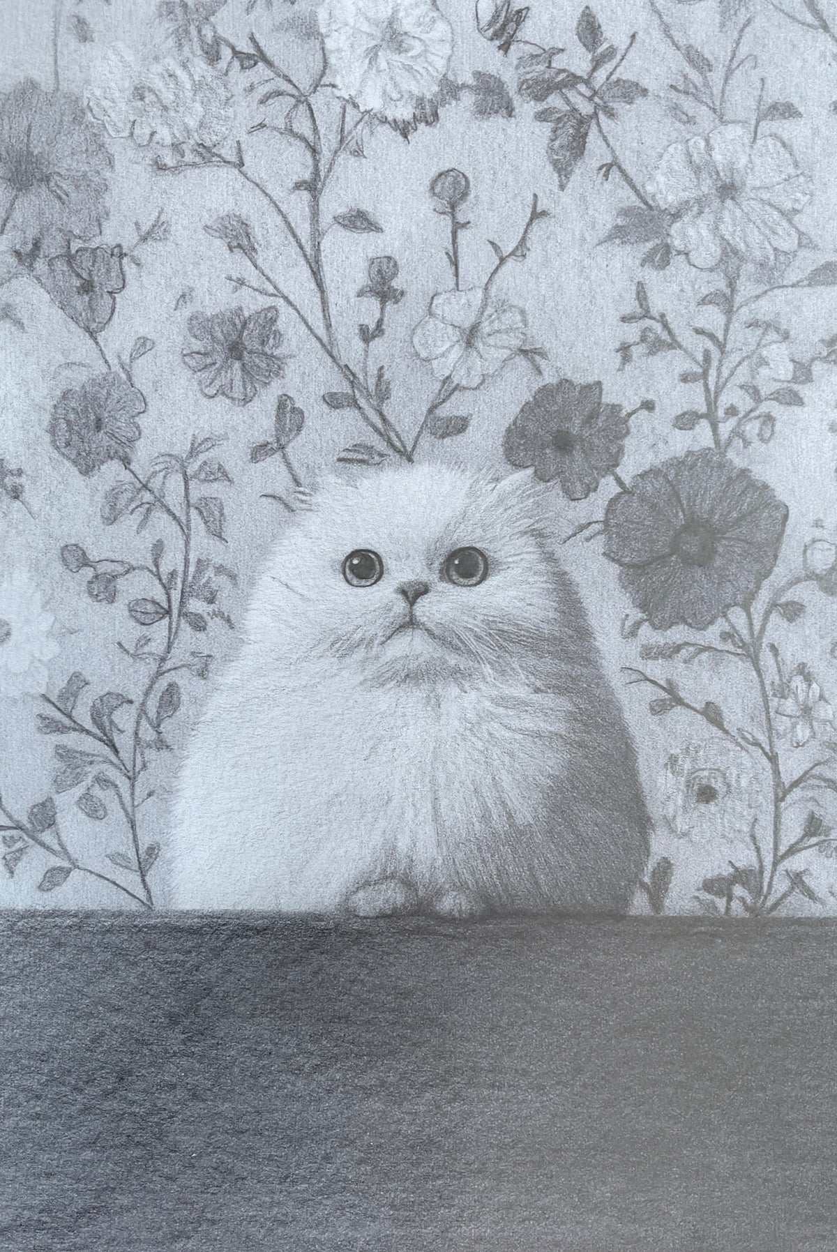MEFREEK Seth Jennemann Graphite Pencil Drawing of a fluffy wide-eyed cat sitting against a dense floral wallpaper background, rendered in soft grayscale with detailed fur texture, rounded features, and intricate botanical patterns creating a playful yet refined composition