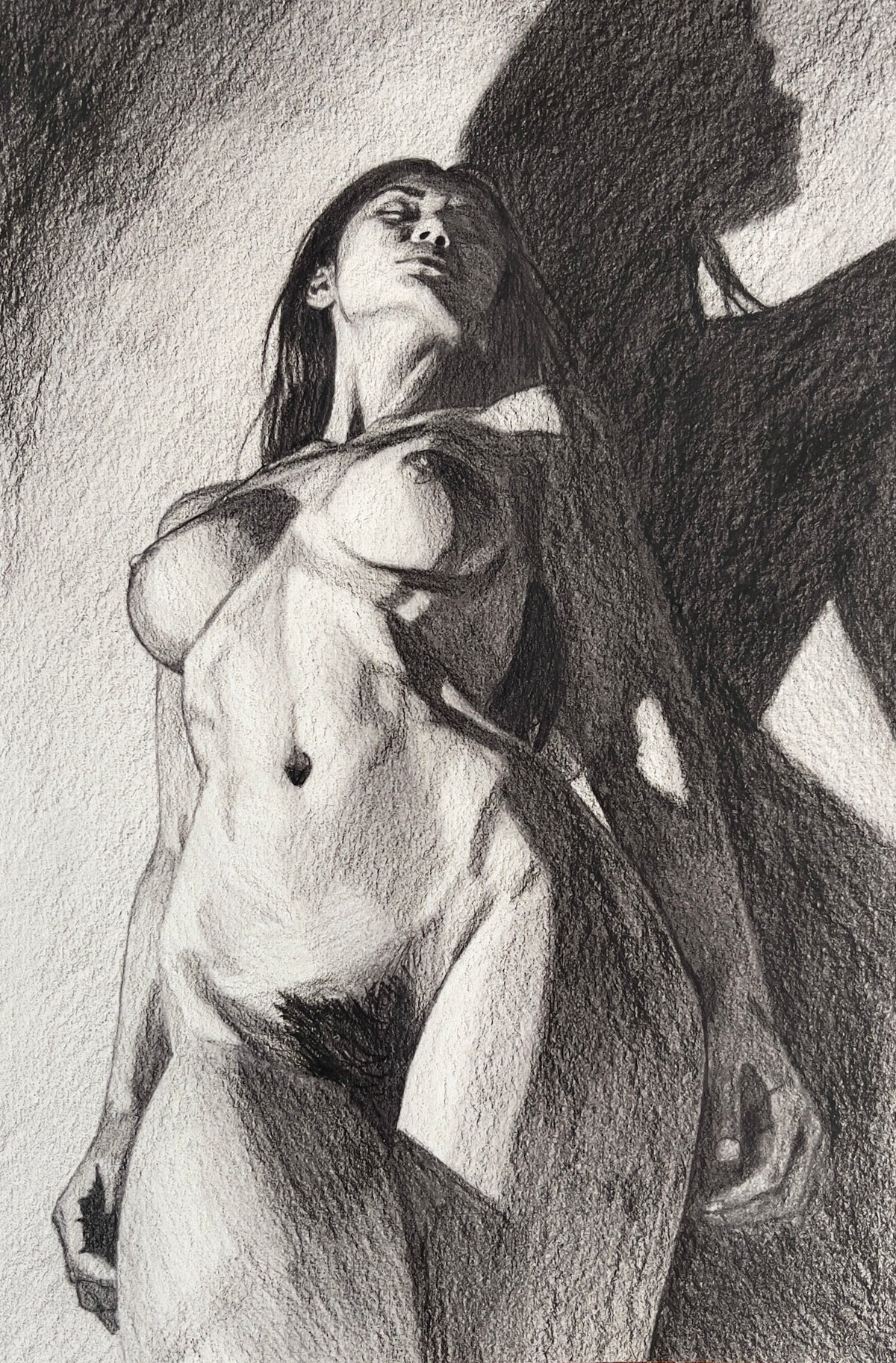 MEFREEK Seth Jennemann Graphite Pencil Drawing of a standing nude female figure viewed from a low angle with dramatic lighting, strong shadow cast across the wall, emphasizing musculature, form, and contrast with expressive tonal depth and textured shading