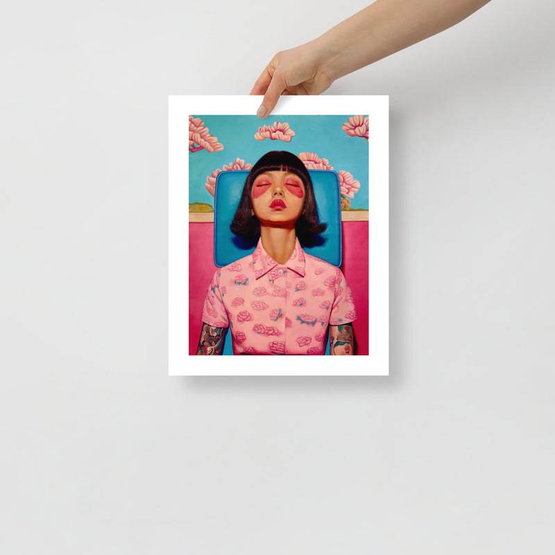 MEFREEK Seth Jennemann Open Edition Print “Infinity Loops And Other Dead Ends” — contemporary fine art print featuring a woman in a pink floral shirt with tattoos, sitting in a blue chair against a bright pink wall, shown unframed and held by a person.