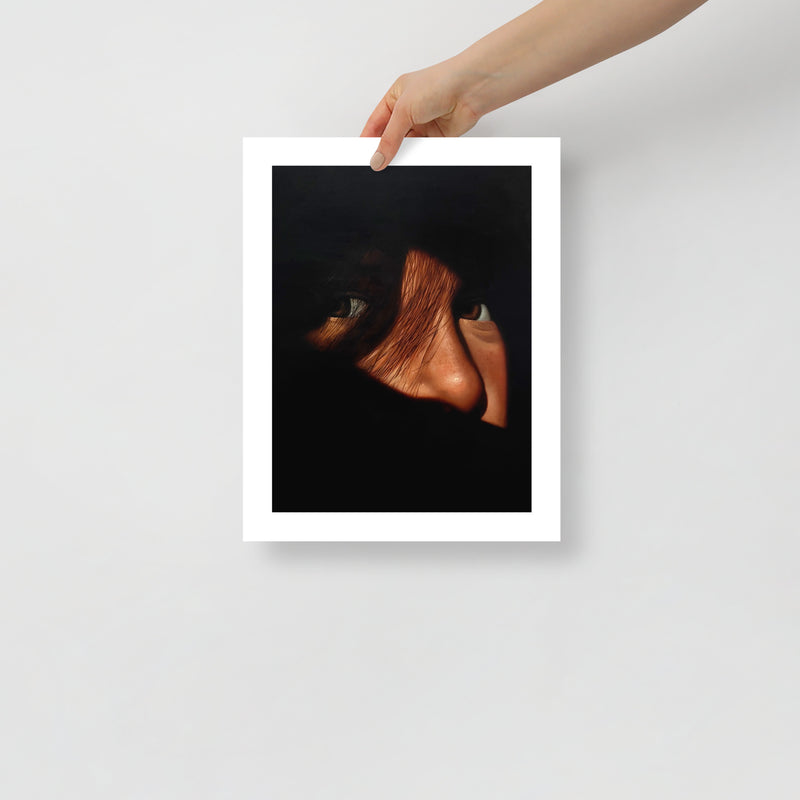MEFREEK Seth Jennemann Open Edition Art Prints Indoor Thoughts In An Outside Voice – Unframed fine art print held by hand against a light gray background, featuring a mysterious close-up portrait with two watchful eyes, warm skin tones, and strands of dark hair emerging from deep black shadows, surrounded by a clean white border.