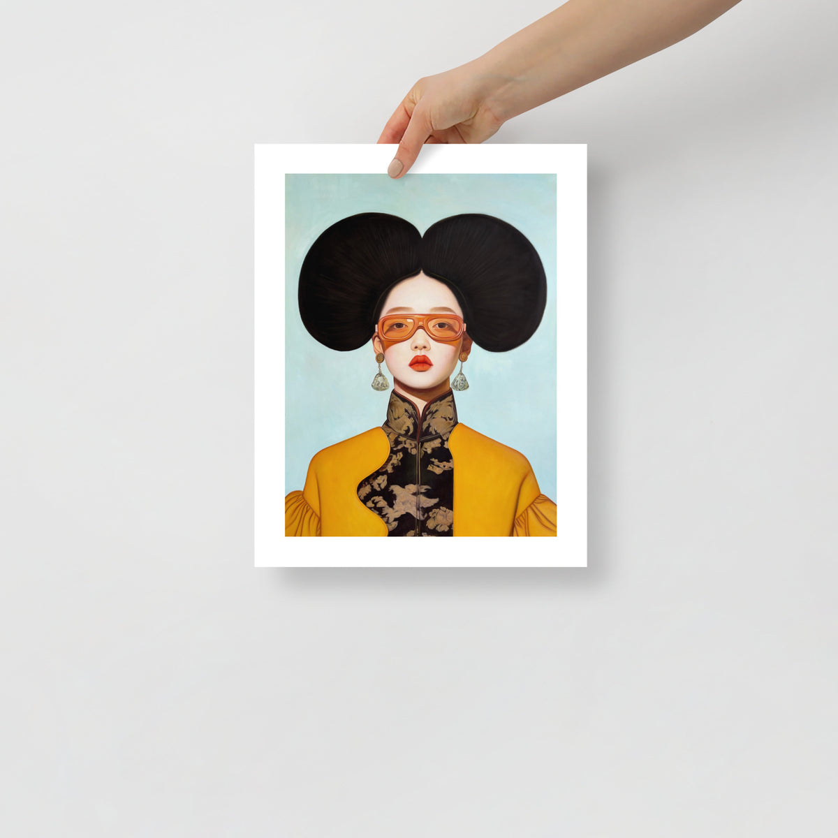 MEFREEK Seth Jennemann Open Edition Print surreal portrait of a woman with large sculptural black hair and orange tinted glasses, intricate patterned high collar outfit in yellow and black, presented as a physical fine art print held by a hand against a minimal neutral background