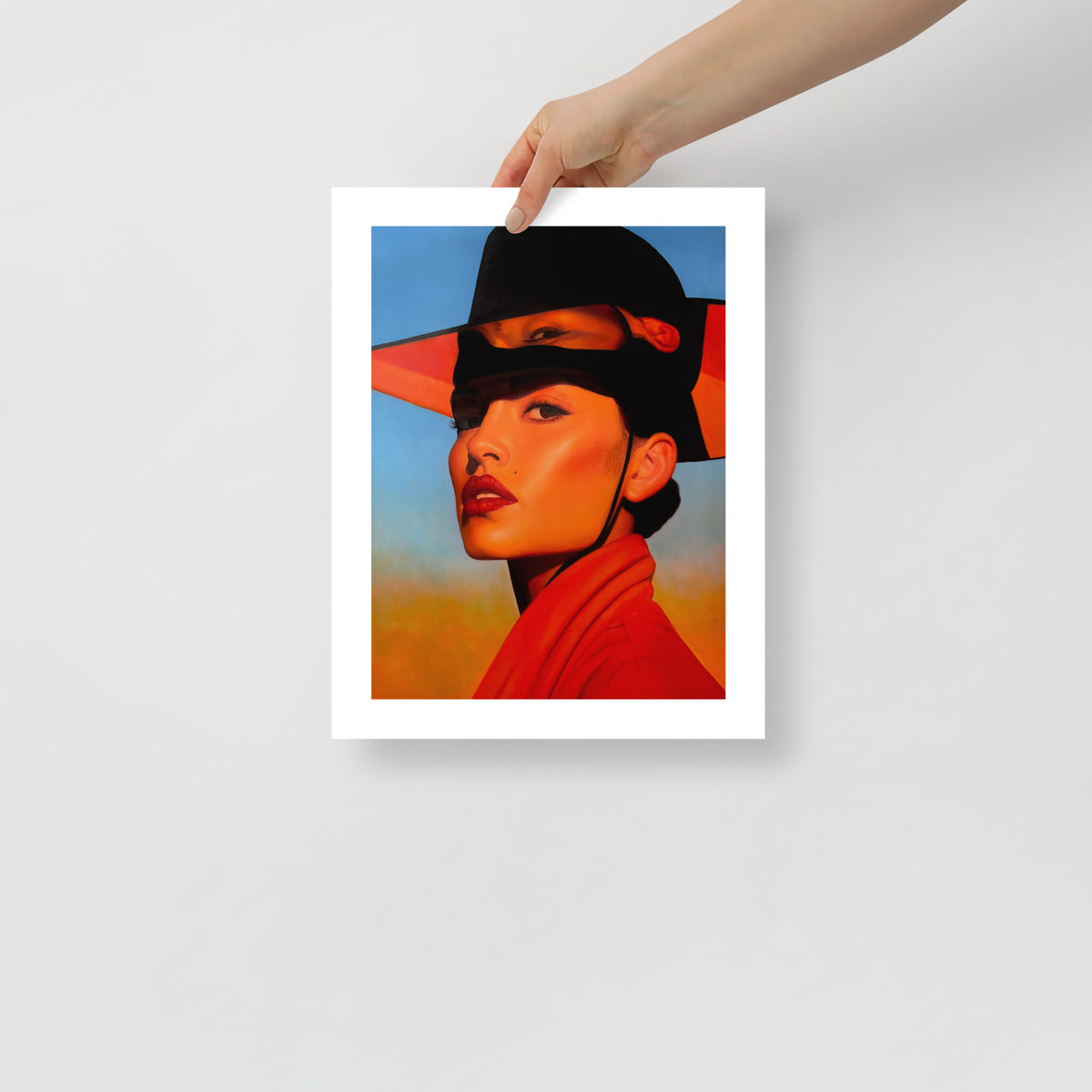 MEFREEK Seth Jennemann Open Edition Art Prints Kept The Change And Called It Me – Unframed fine art print held by hand against a light gray background, showing a striking portrait of a woman in a red-orange garment and oversized black hat with surreal overlapping facial features, illuminated in warm orange light against a contrasting blue and yellow backdrop.