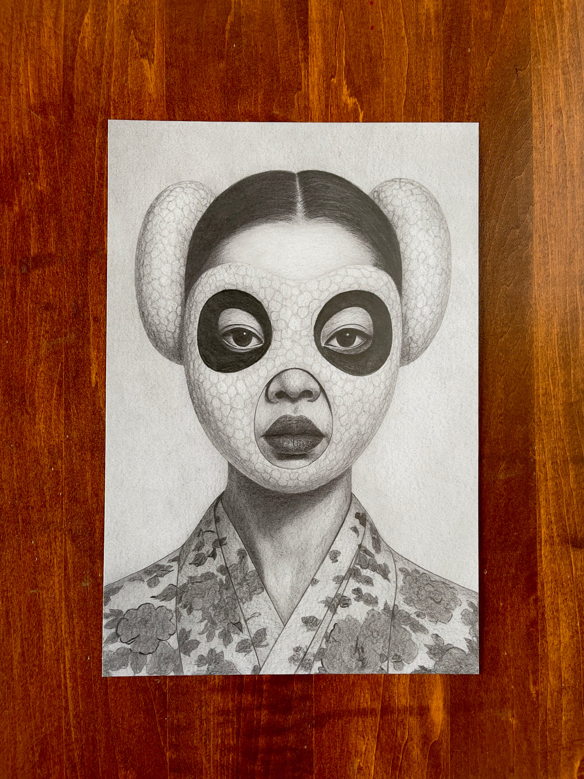 Seth Jennemann MEFREEK — Melancholy and the Fleshlight of Sadness, graphite pencil drawing in hyperreal contemporary portrait style. A woman with sleek hair and a panda-inspired sculptural mask stares forward while wearing a patterned floral robe, blending surreal elegance with quiet intensity.