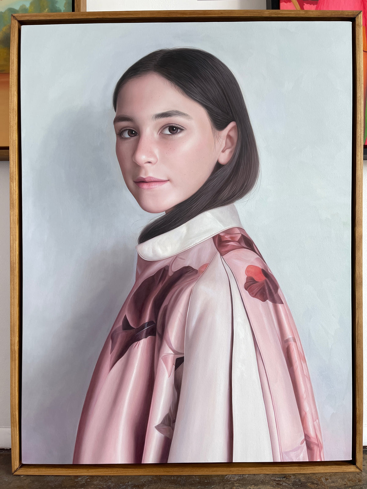 MEFREEK Seth Jennemann Rome Wasn't Programmed In A Day framed hyperreal oil painting portrait of a young woman with brown hair wearing a pink satin garment with floral patterns, soft gray background, contemporary realism portrait painting
