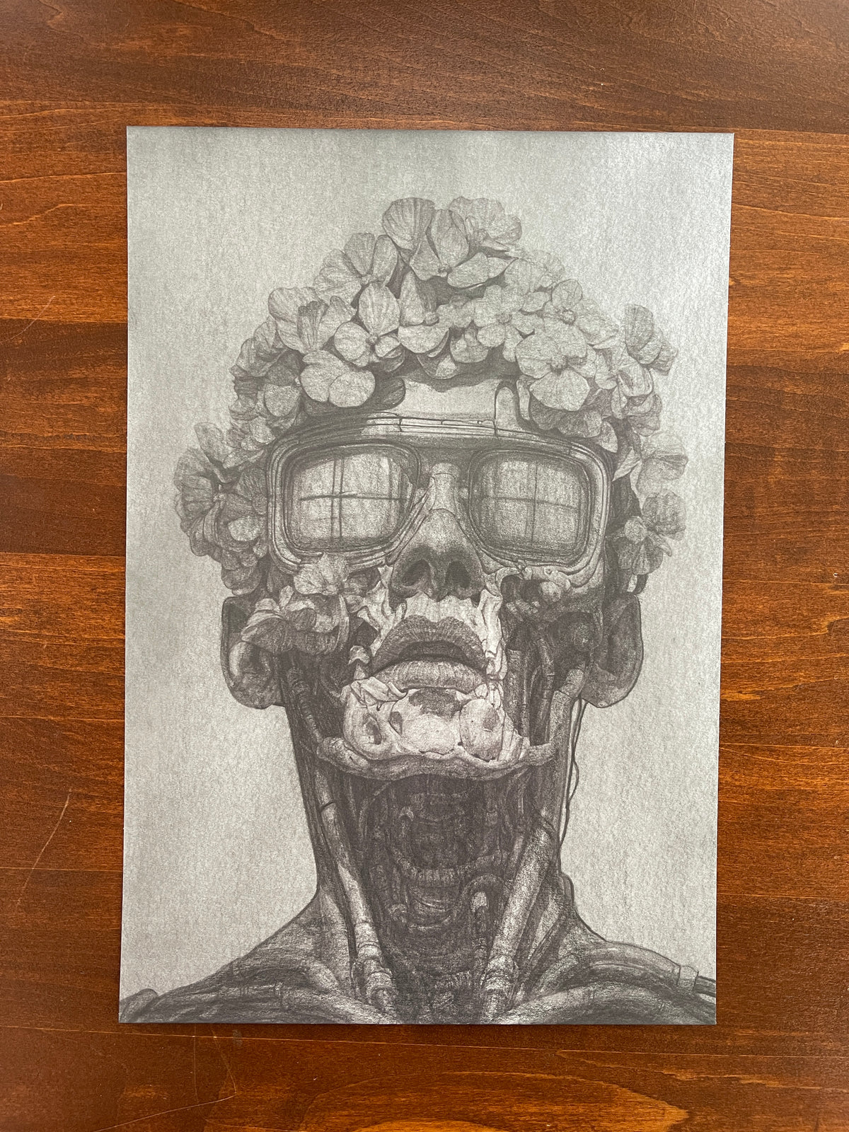 Seth Jennemann MEFREEK Synthetic Bloom – graphite drawing in hyperreal pop surrealism style portraying a humanoid figure with exposed mechanical anatomy, wearing large glasses and crowned with blooming flowers, symbolizing the collision of organic life and synthetic form.
