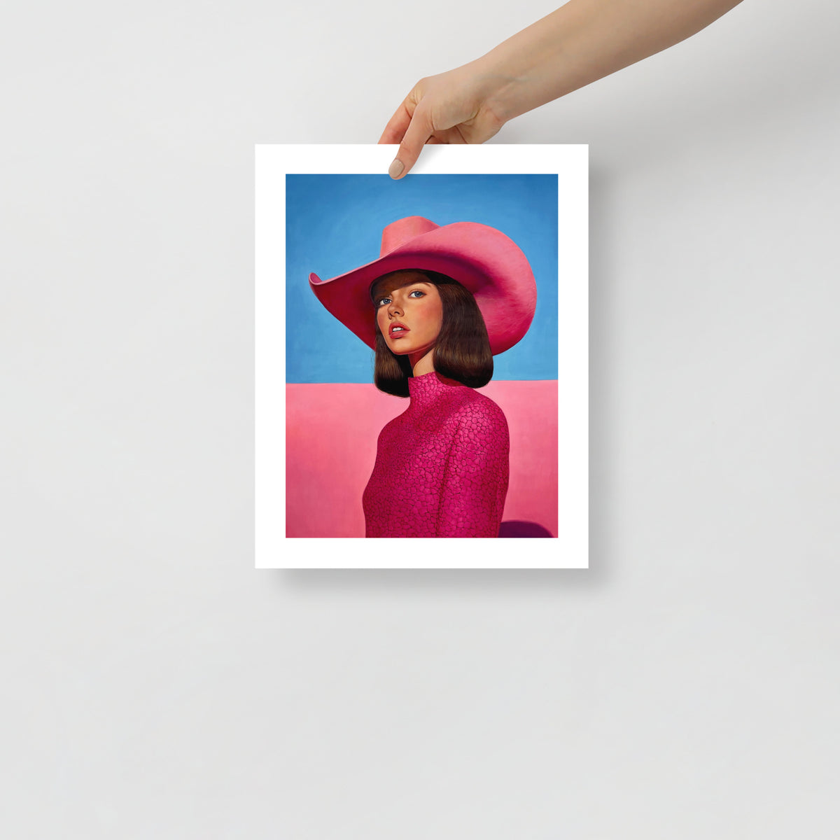 MEFREEK Seth Jennemann Open Edition Print stylized portrait of a woman in a vivid pink cowboy hat and patterned high neck garment, smooth skin tones and clean composition contrasted by a pastel blue and pink split background in a refined surreal realism style