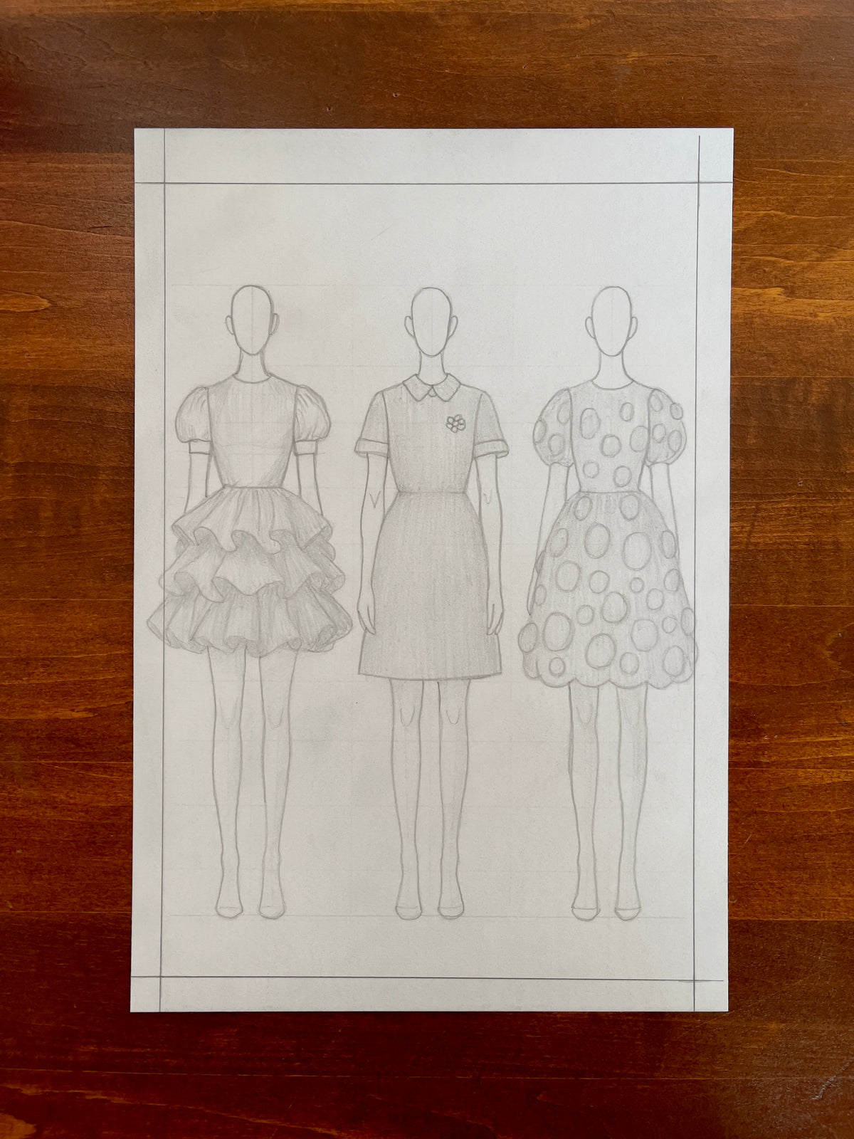 Seth Jennemann MEFREEK — This Only Ends When You Do, graphite pencil fashion illustration in conceptual sketch style. Three faceless figures wear structured short dresses featuring puff sleeves, layered ruffles, and circular textures, drawn with fine linework on a light paper background.