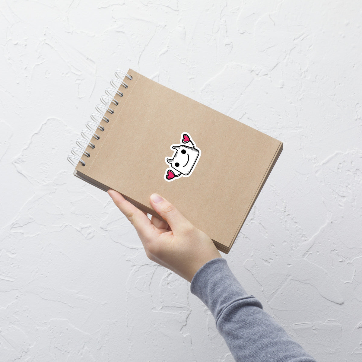 Hand holding a brown notebook with a white background