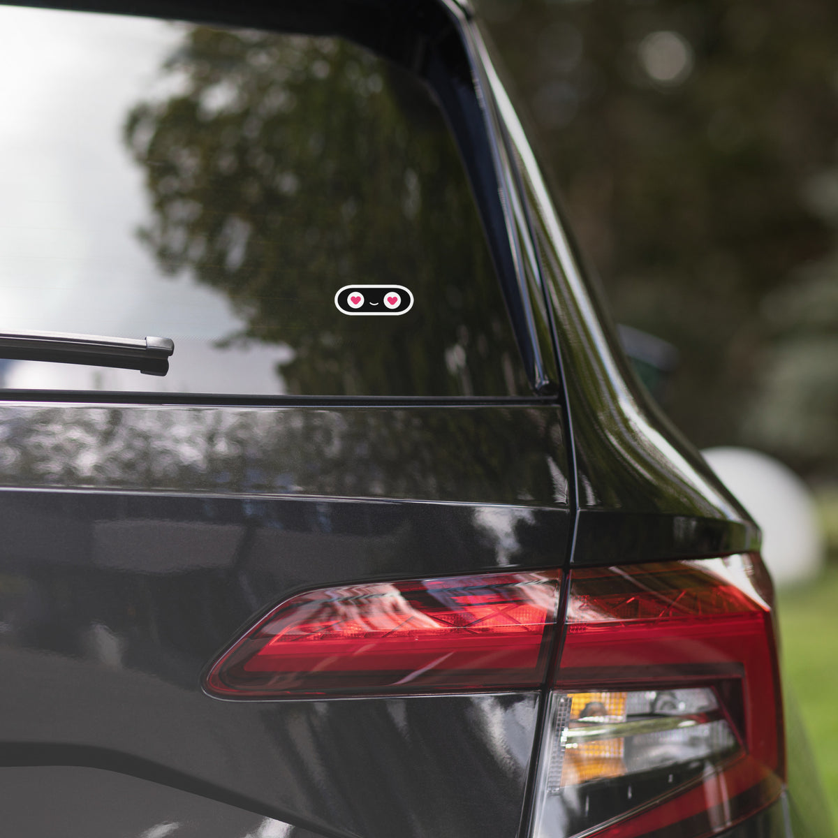 Car's rear end with a visible brand logo against a blurred natural background