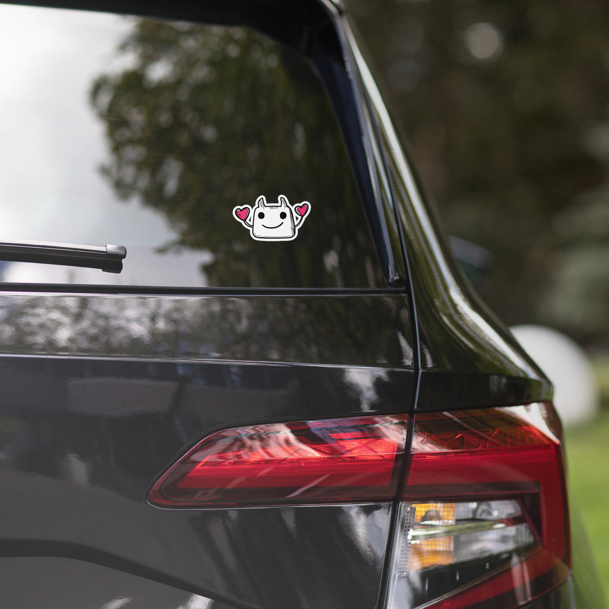 Car rear with a sticker on the window, blurred greenery in the background
