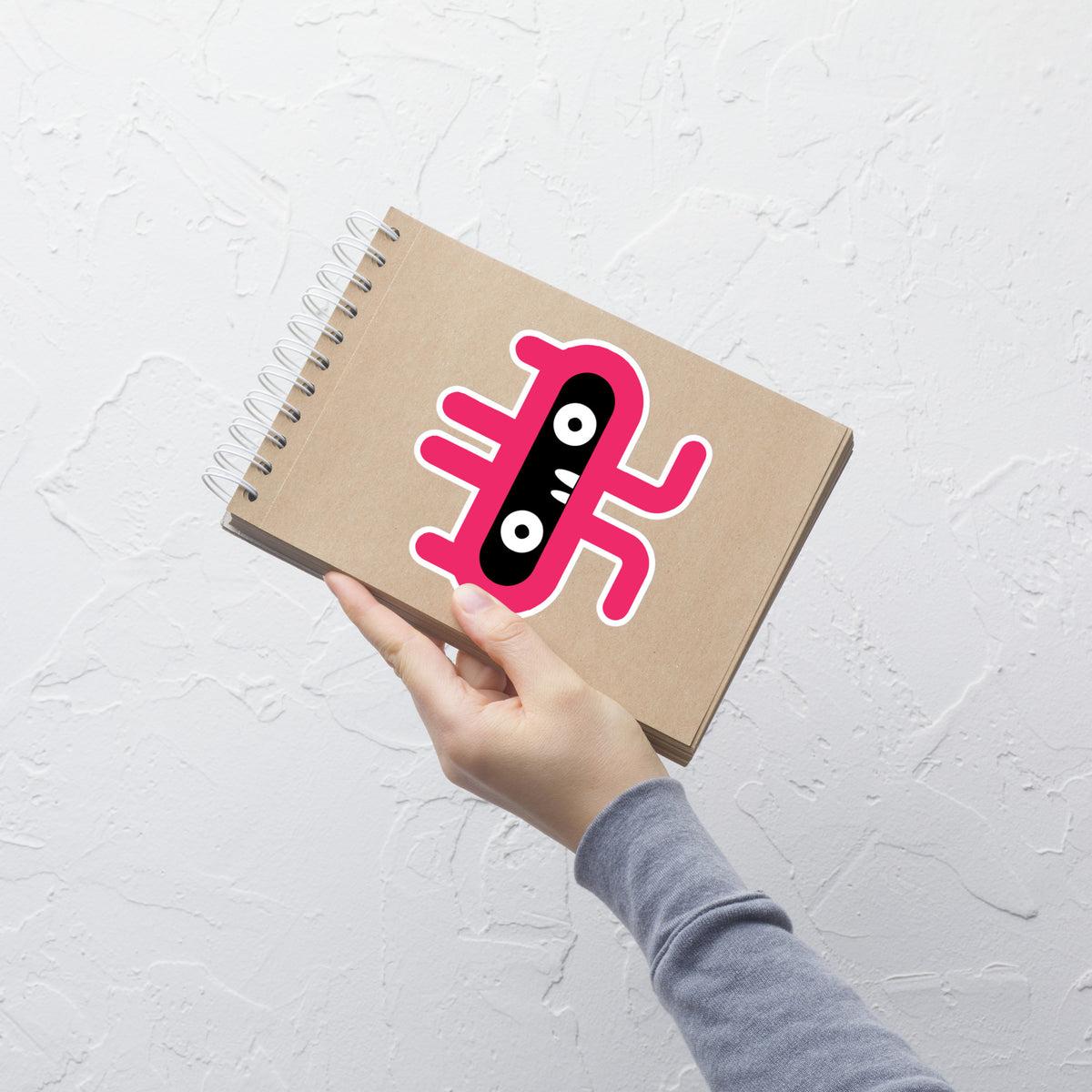 Notebook with a pink and black design held by a hand on a light gray background