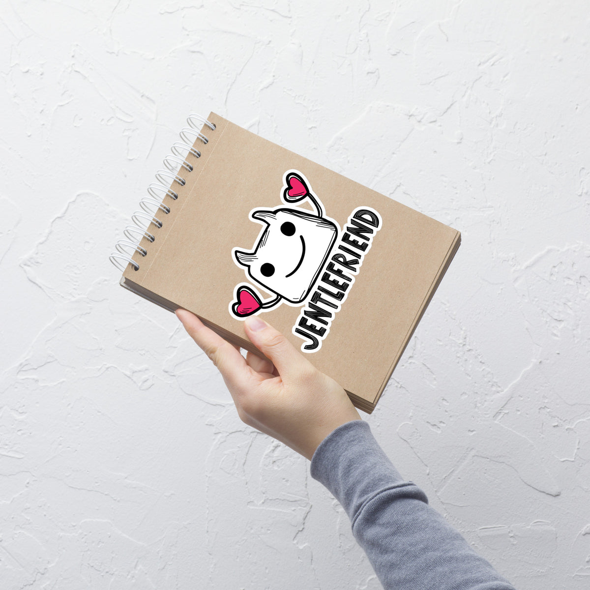 Notebook with 'Jentlefriend' design held by a hand on a light gray background